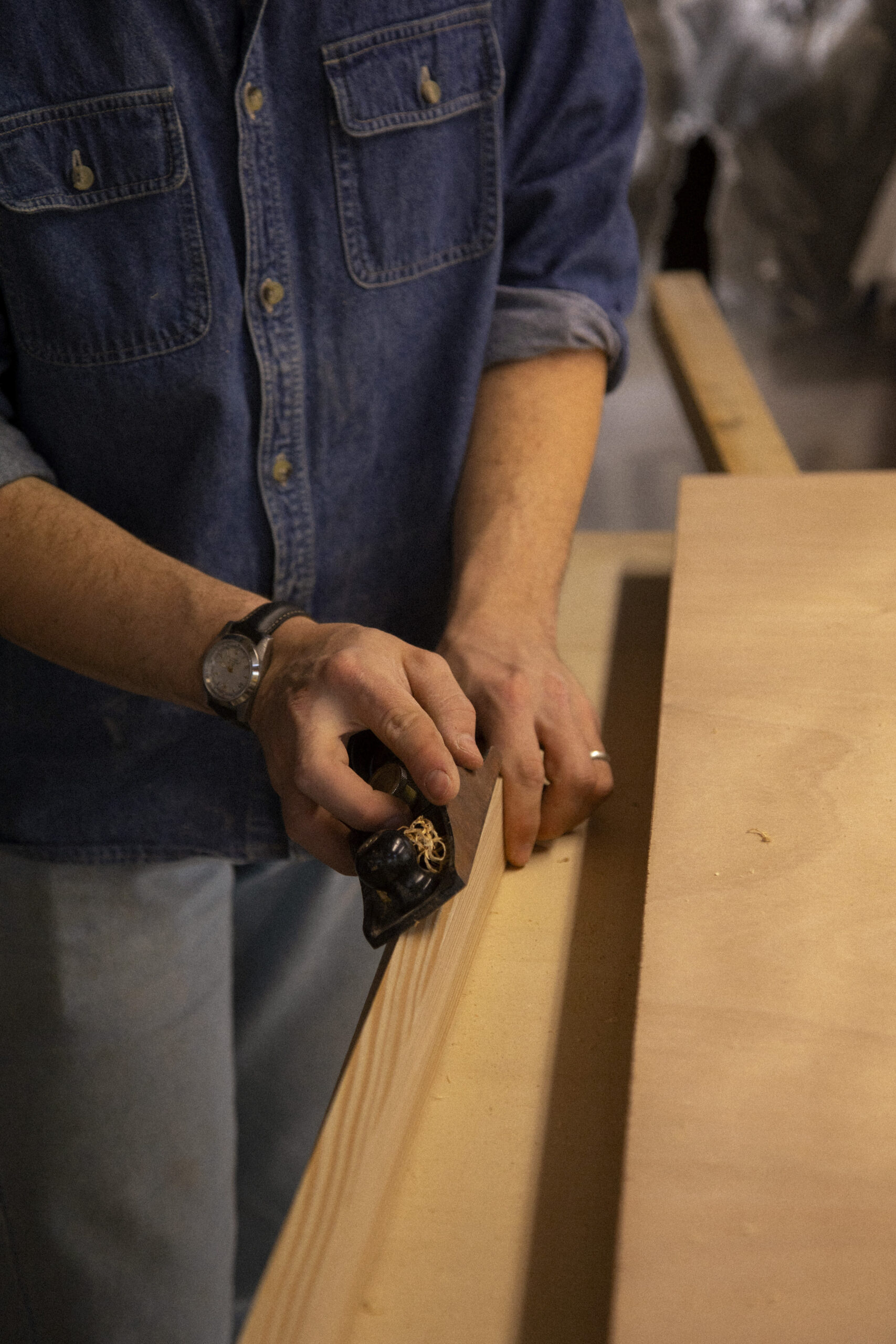 Mains rabotant les champs d'une planche de bois pour un meuble sur-mesure.